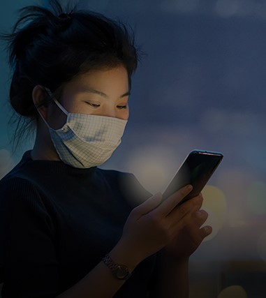 A Woman Using A Smartphone Wears A Medical Face Mask To Avoid The